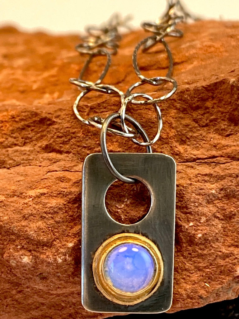 Hand-crafted, one-of-a-kind necklace sterling silver pendant featuring: Luminous opalite stone, purple hue Set in a 14k gold bezel. 19" sterling silver chain with a handcrafted clasp. 7/8" x 1/2"
