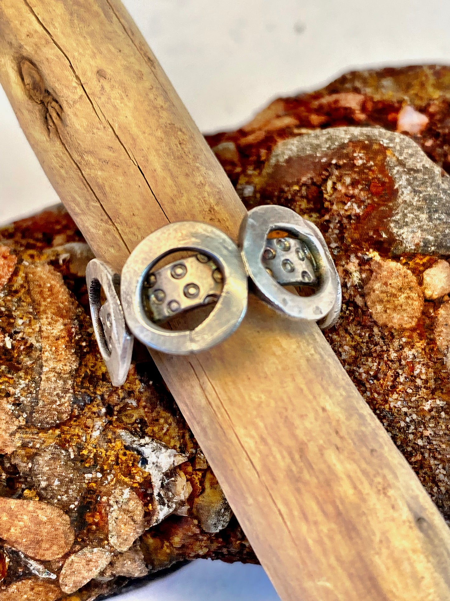 One-of-a-kind sterling silver ring adorned with four smashed hoops around a band textured with tiny stamped circles. Size 7.5.