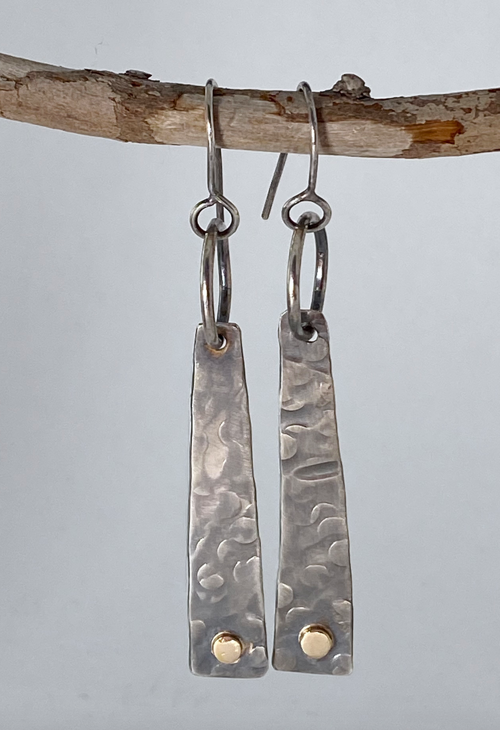 Evocative long sterling silver tablet-shaped earrings. 14k gold embellishments. Hand-stamped texture. A flattering shape for almost any face. Stellae are 1-1/5" long x 3/8" wide at base. Handmade ear hook and ring add length. Style: rustic, boho, elemental, earthy yet elegant