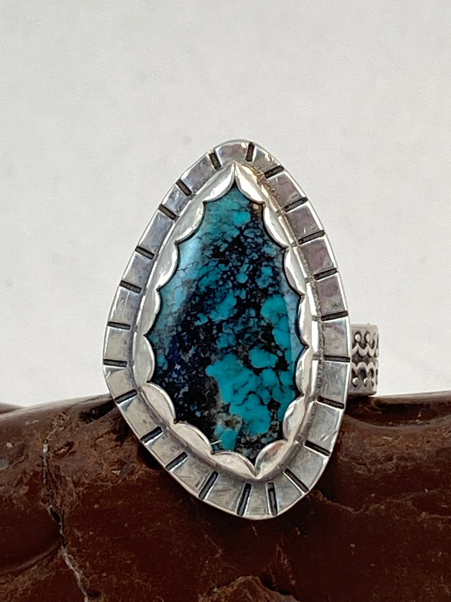 Gorgeous turquoise stone set in scalloped bezel on textured backplate atop beautifully textured ring band