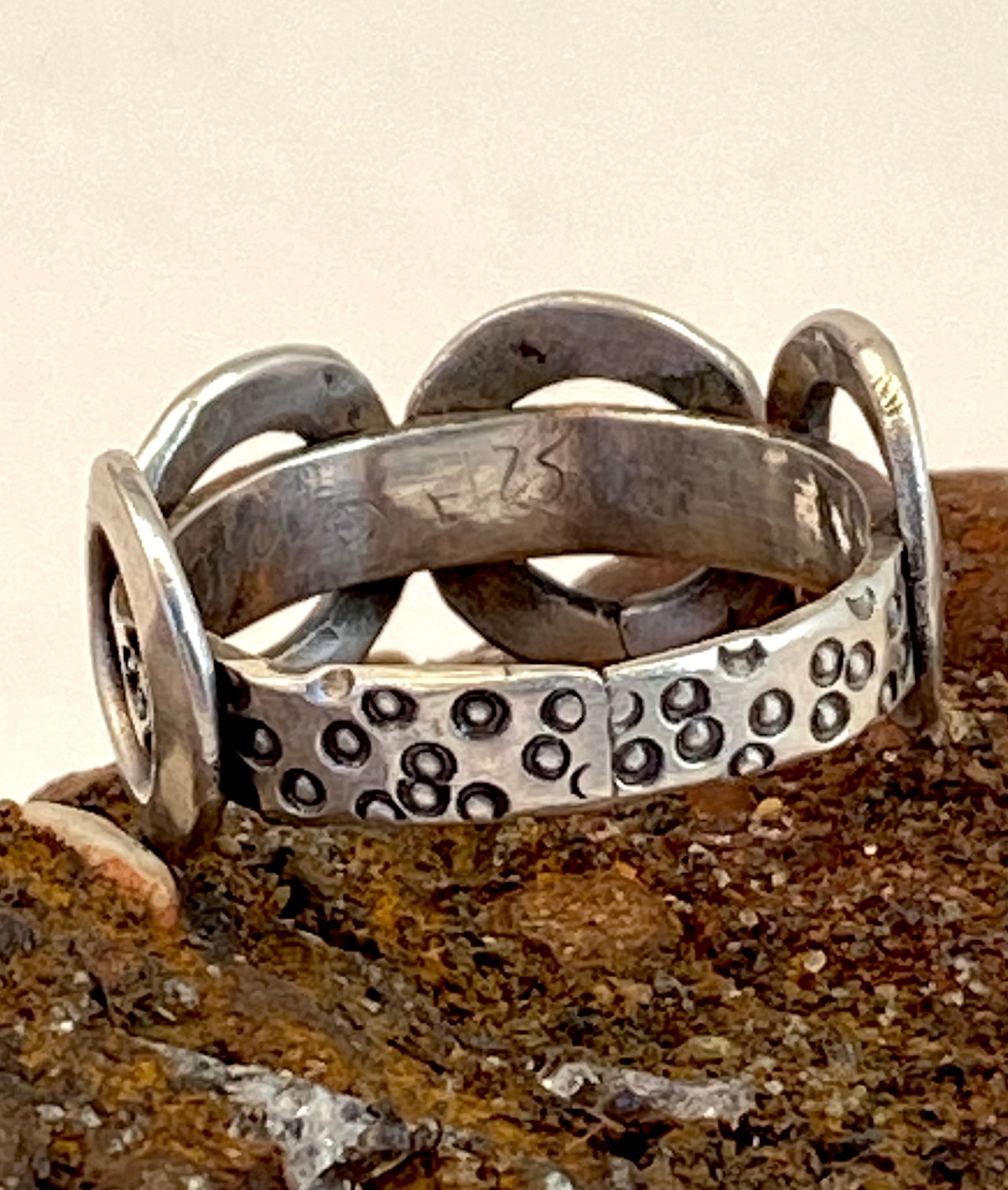 One-of-a-kind sterling silver ring adorned with four smashed hoops around a band textured with tiny stamped circles. Size 7.5.