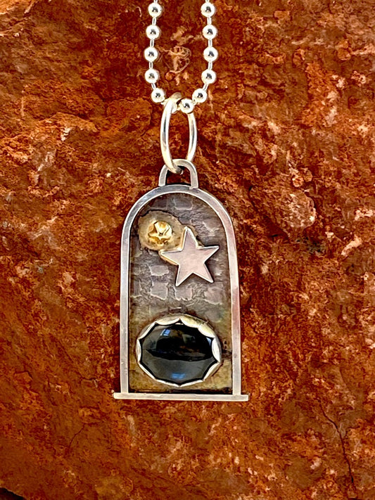 At the heart of this sterling silver portal is a hypersthene crystal, which promotes clear thinking and enhances self-confidence.  The background features a unique grid pattern   14k Gold and sterling silver star embellishments add magic to the piece  17" ball chain  1.25 x .75"